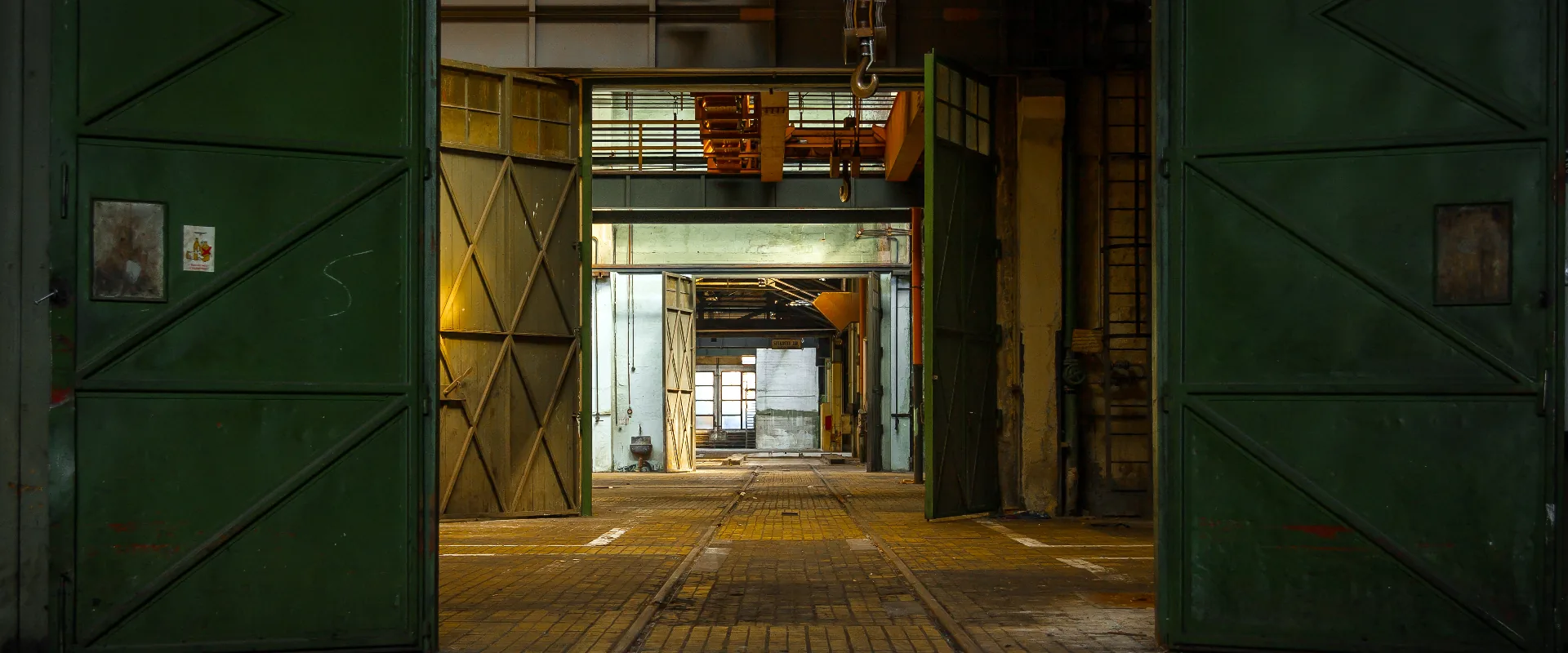 Open green industrial doors leading into a long factory hall in the specialist manufacturing network