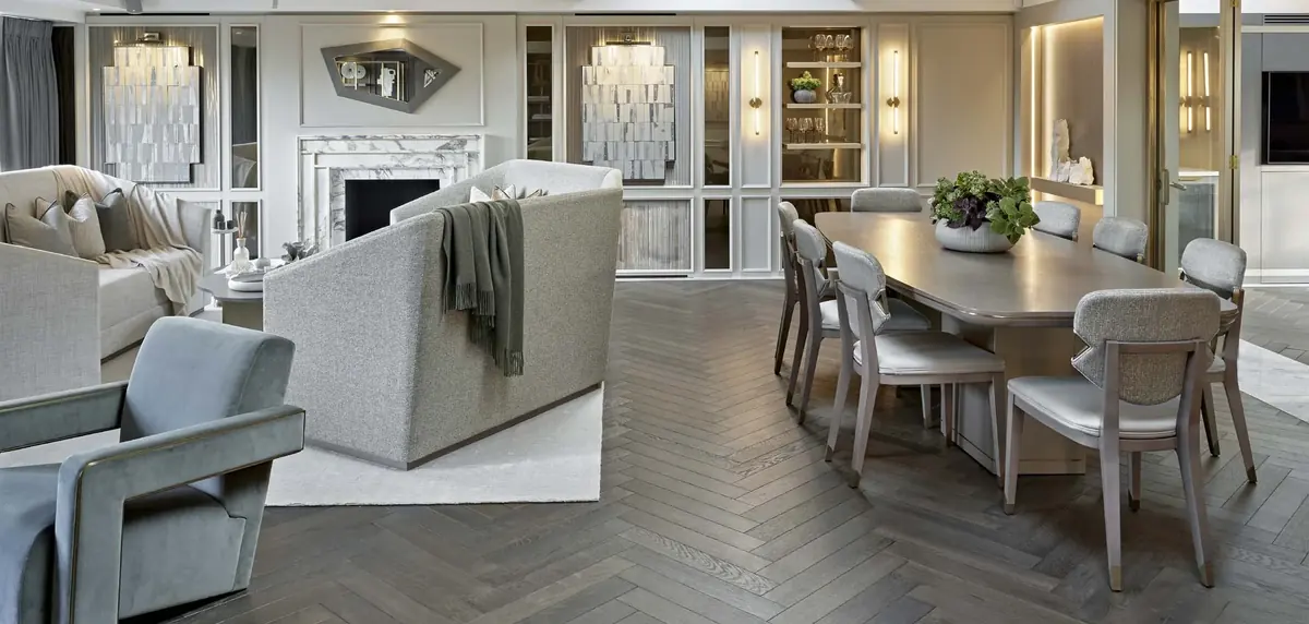 Open-plan living and dining room with herringbone floor, long dining table and grey sofa at Eaton Square