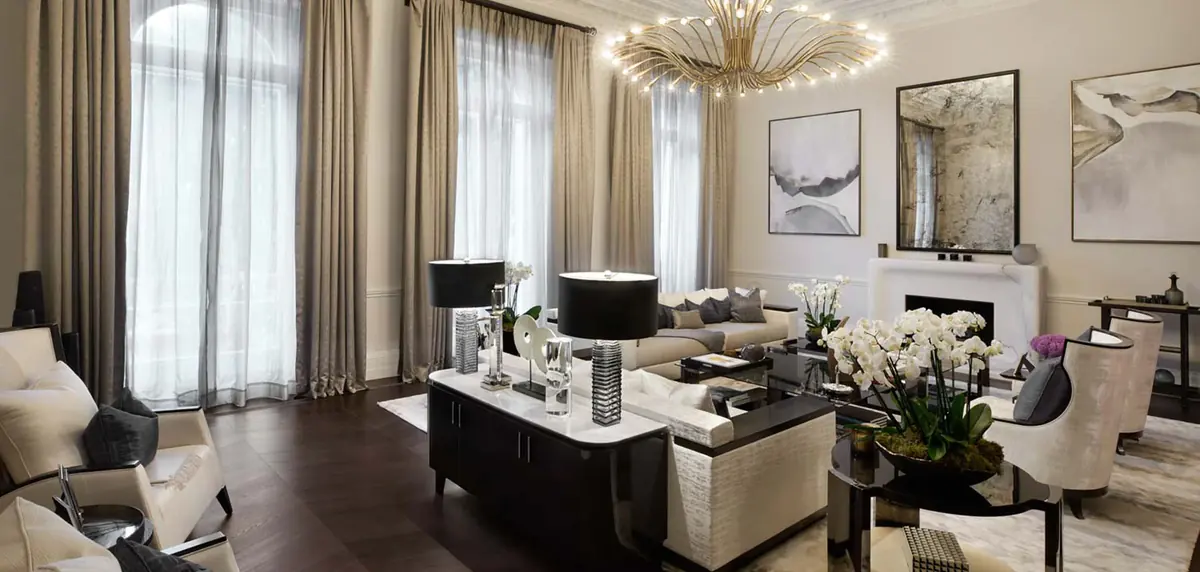Belgrave apartment living room with sunburst chandelier, long cream sofa and dark lacquer coffee table