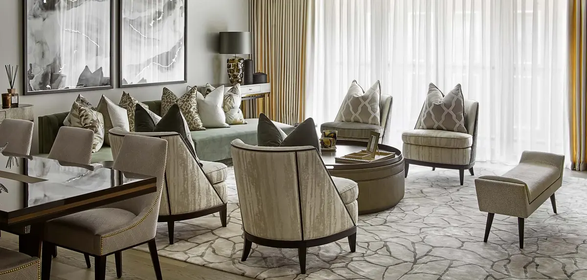 Grey-green sofa and striped armchairs on a patterned rug in a Kensington residence living room