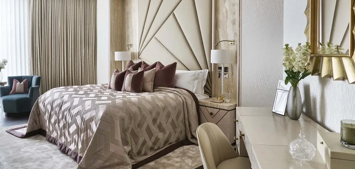 Bedroom with fan-shaped upholstered headboard, patterned bedspread and gilt mirror at One Hyde Park