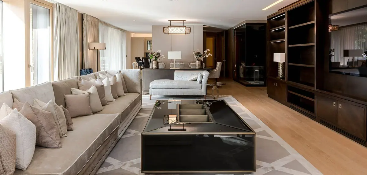 Open-plan Kensington apartment living room with long cream sofa and walnut shelving