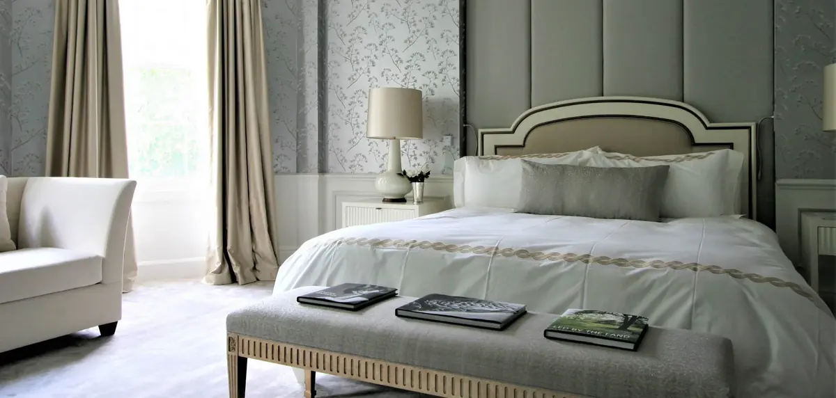 Bedroom with grey panelled headboard, upholstered bench and patterned wallpaper, Old Queen Street Townhouse