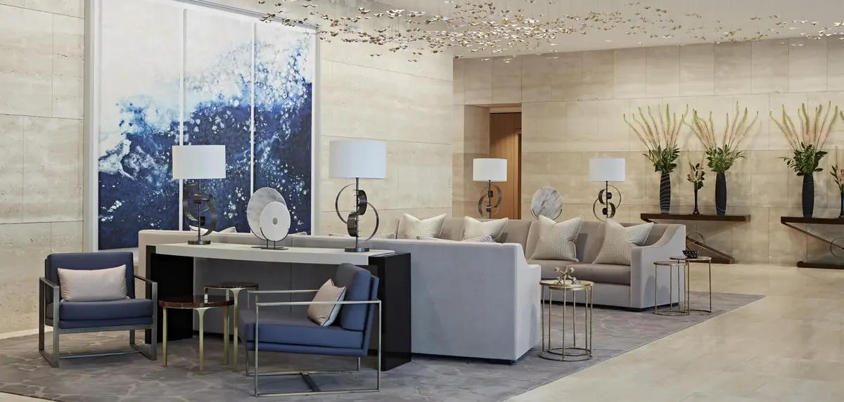 Lobby lounge with grey sofas, navy armchairs and ocean-blue artwork under a decorative ceiling, One Kensington Gardens