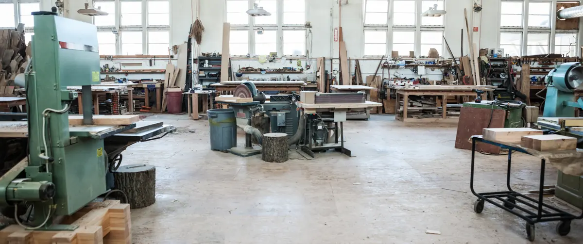 Bespoke joinery workshop floor with band saw, woodworking machines and benches beneath tall windows