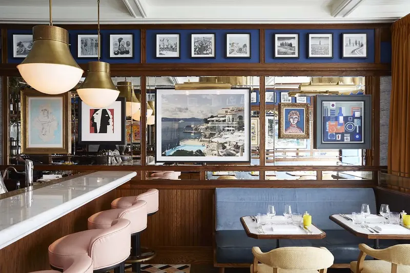 Brass pendants with glowing white shades above a bar with pink stools at Chucs, bespoke lighting