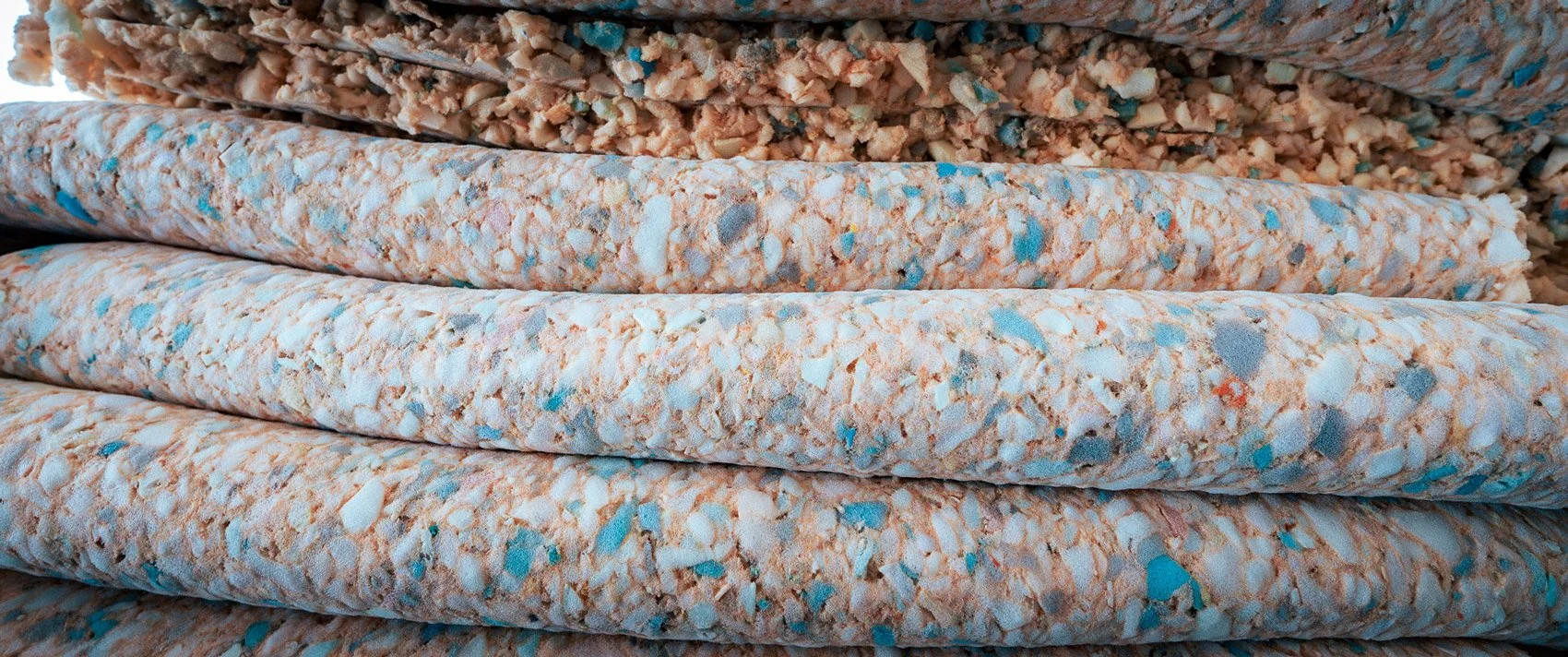 Close rolls of rebonded foam in speckled blue, orange and cream colours