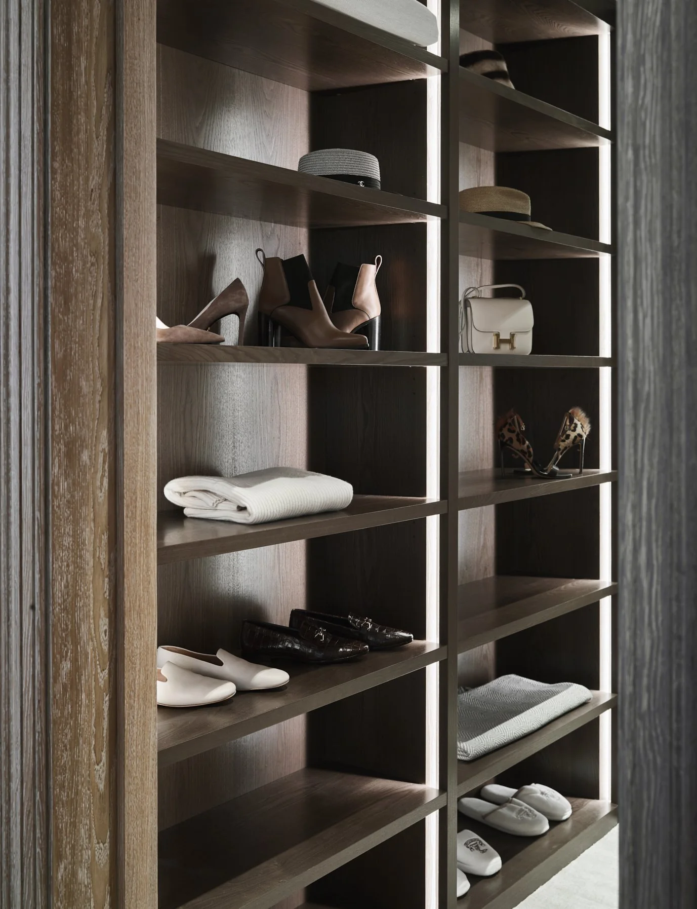 Dark timber display shelving holding shoes, a handbag, a hat and folded knitwear, fitted retail style joinery