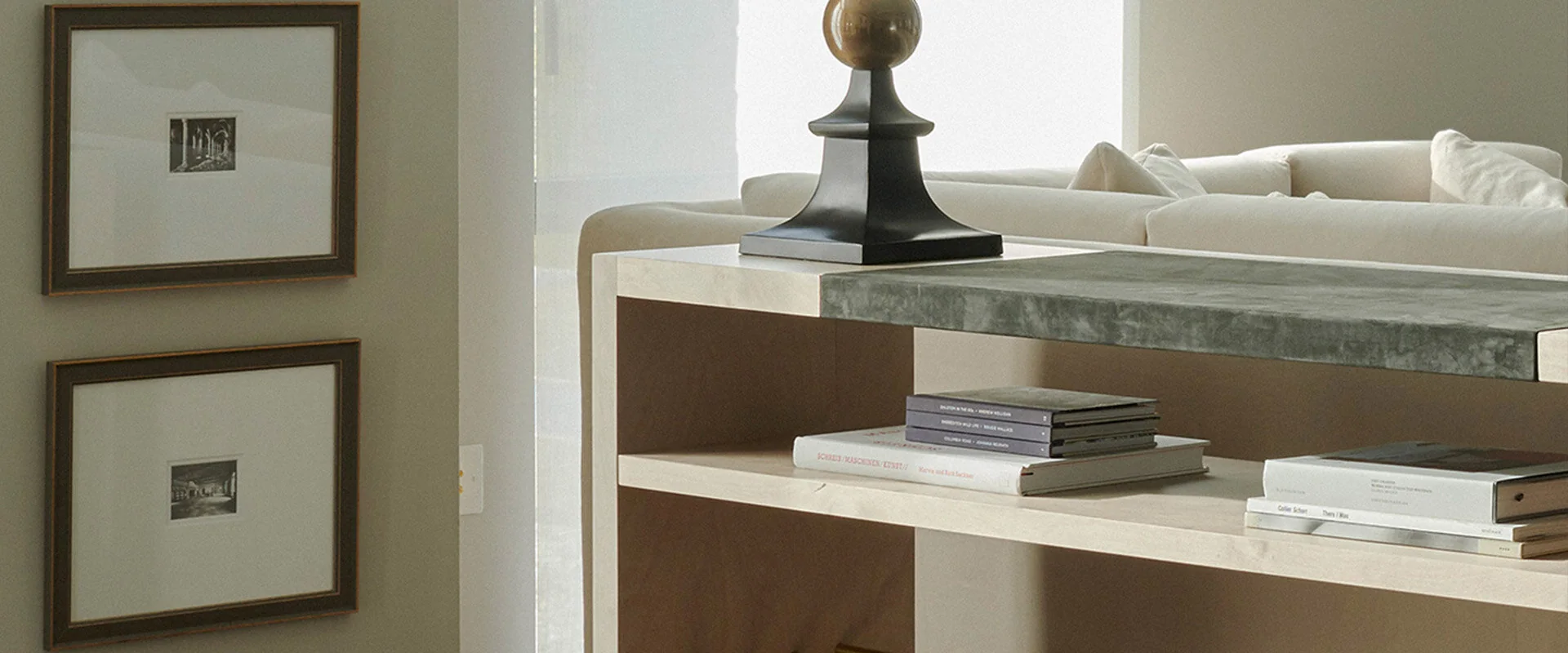Limed oak console with grey stone top and open shelf of books behind a cream sofa, bespoke console table