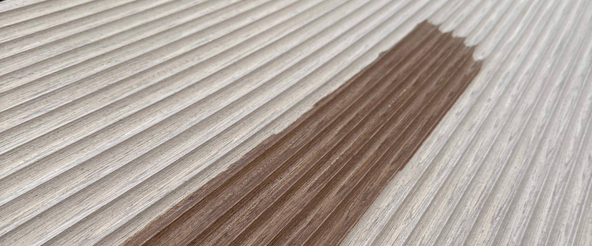 Fluted grey-washed oak panel with a darker finish sample patch, close view of the milled grooves