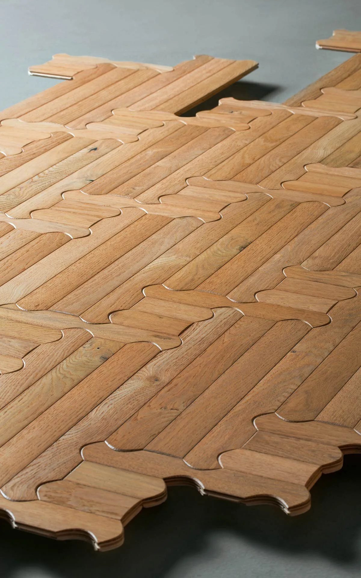 Loose Biscuit oak boards with rounded, interlocking ends laid out on a dark surface