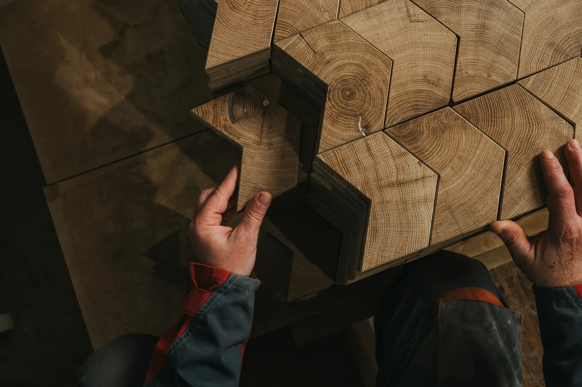 Hands setting an end-grain oak chevron block into an Élément arrangement