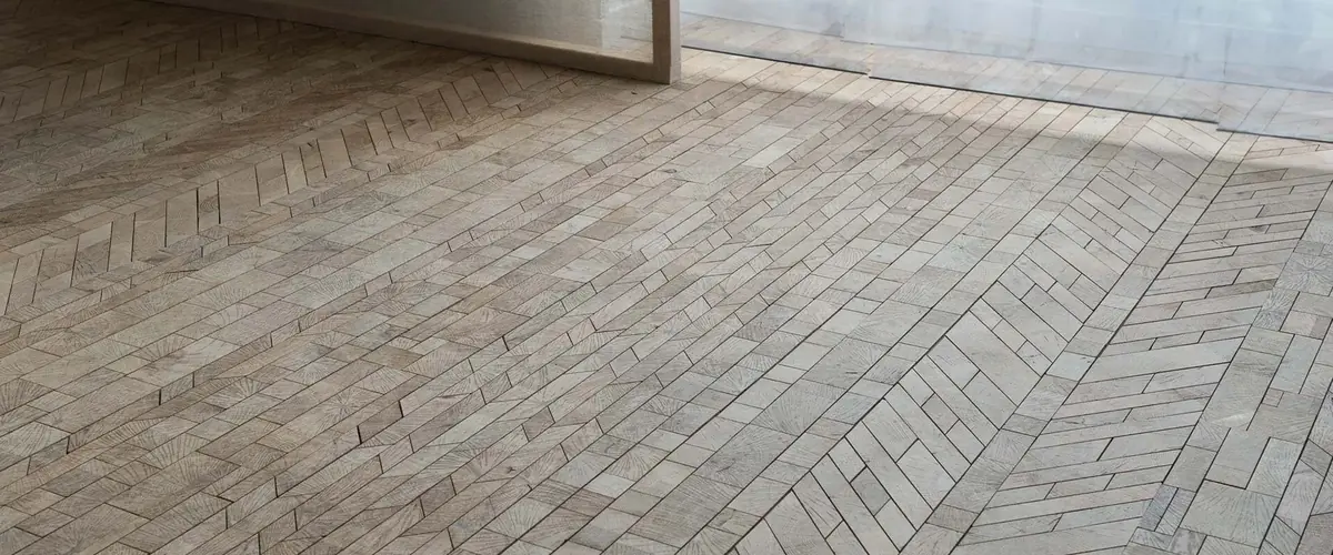 Grey herringbone flooring laid in a bright room, bespoke flooring