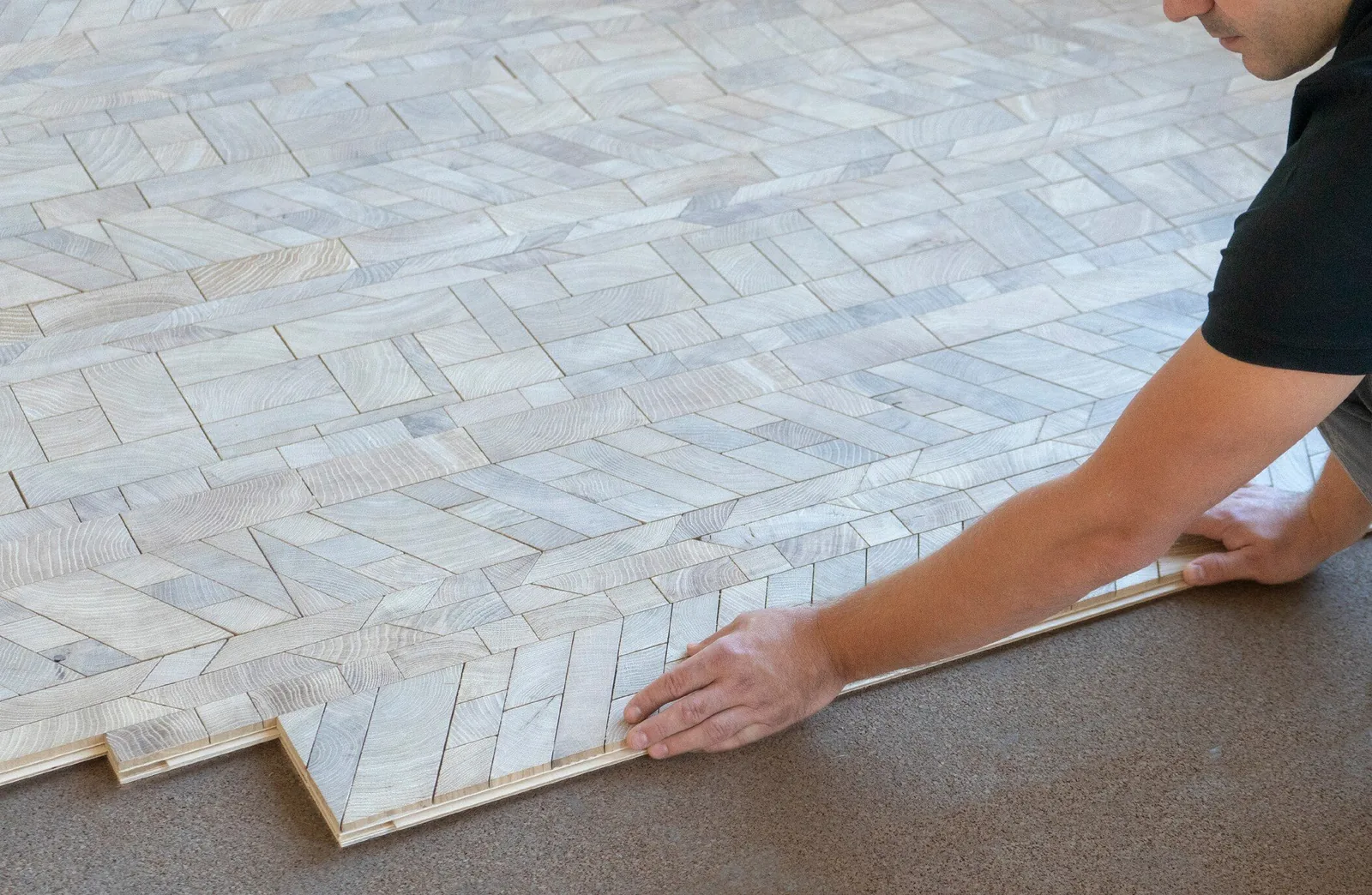 Fitter laying a pre-assembled Forêt end-grain oak board onto a prepared floor