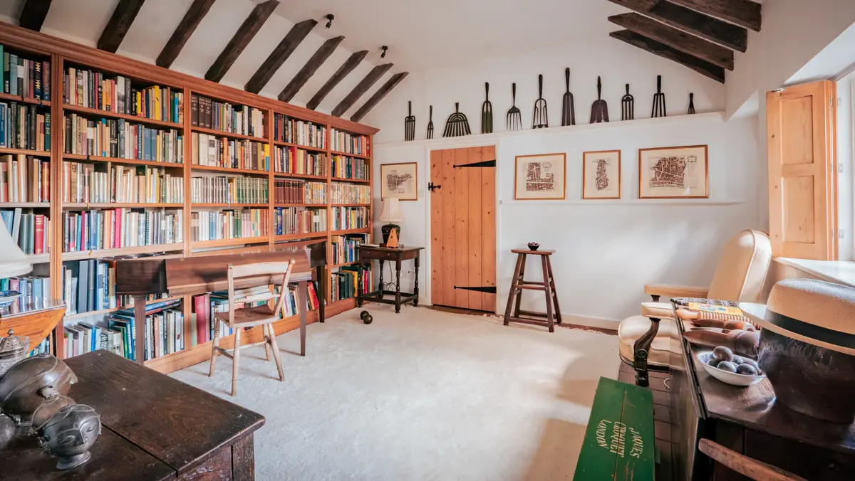 Oak bookcases and beamed ceiling in a bespoke library with reading desk