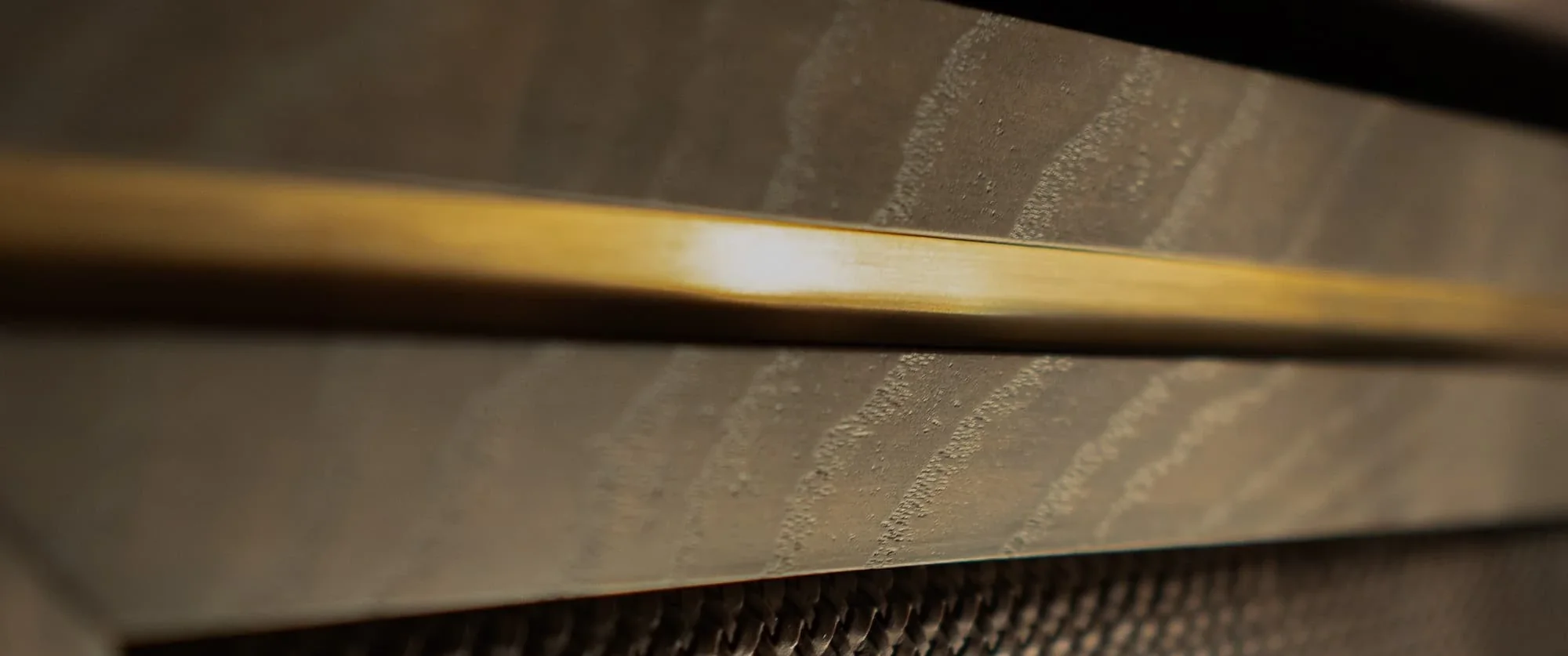 A brass inlay line set flush into grey oak joinery, catching the light — Make Bespoke Studio