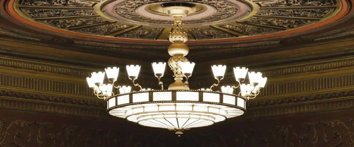 Large bespoke glass and brass chandelier hanging beneath an ornate decorated domed ceiling