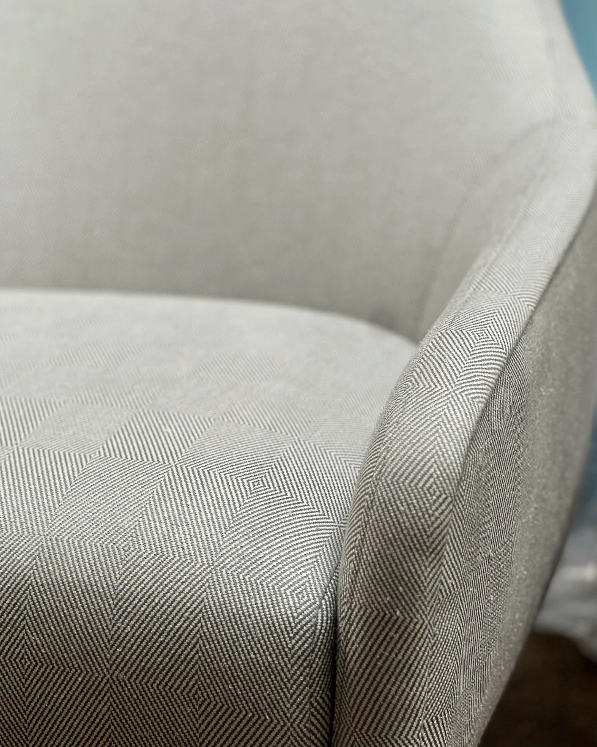 Macro view of the pale diamond-weave upholstery on the lounge chair in the Antibes penthouse, showing the fine woven pattern across the seat and the piped arm.