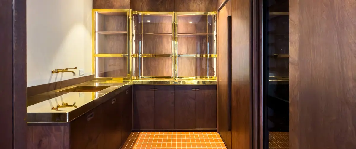 Camberwell House fitted utility alcove with brass framed glass shelving, brass tap and dark timber cupboards