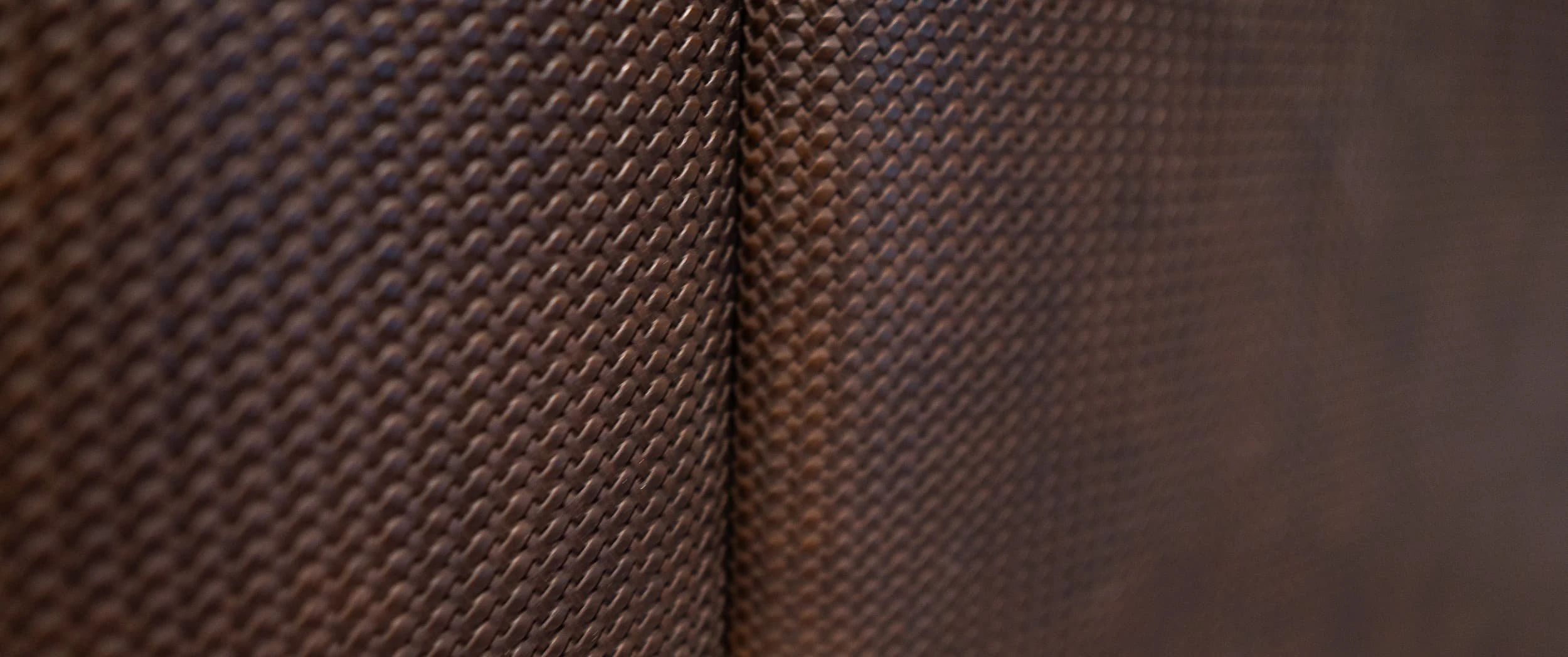 Macro detail of the brown woven leather wall panelling, showing the crisp folded edge where two panels meet in the Country Home Cinema.