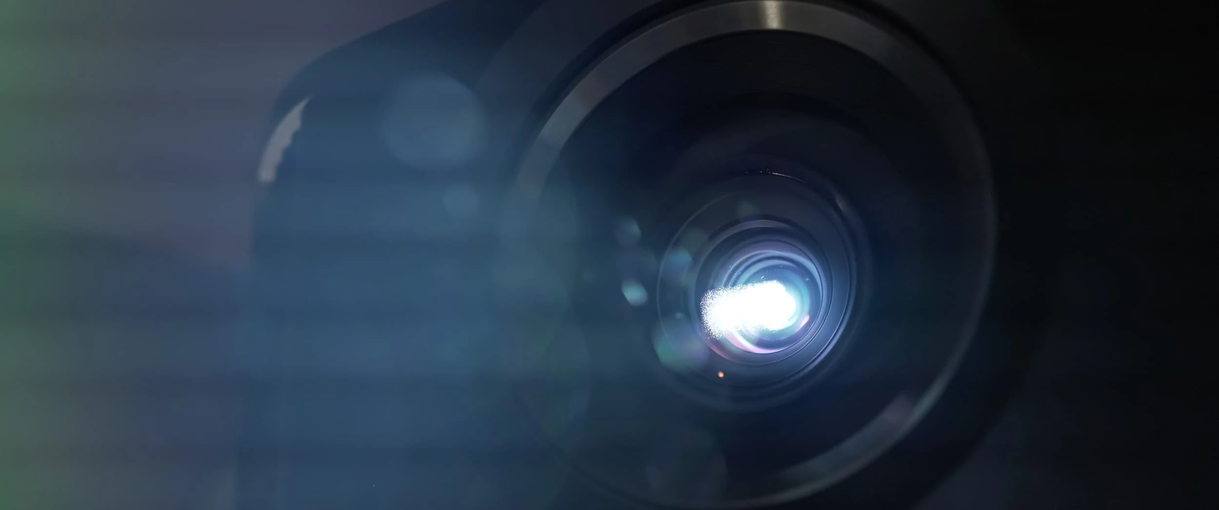 Macro view of the illuminated projector lens throwing its beam in the Country Home Cinema.