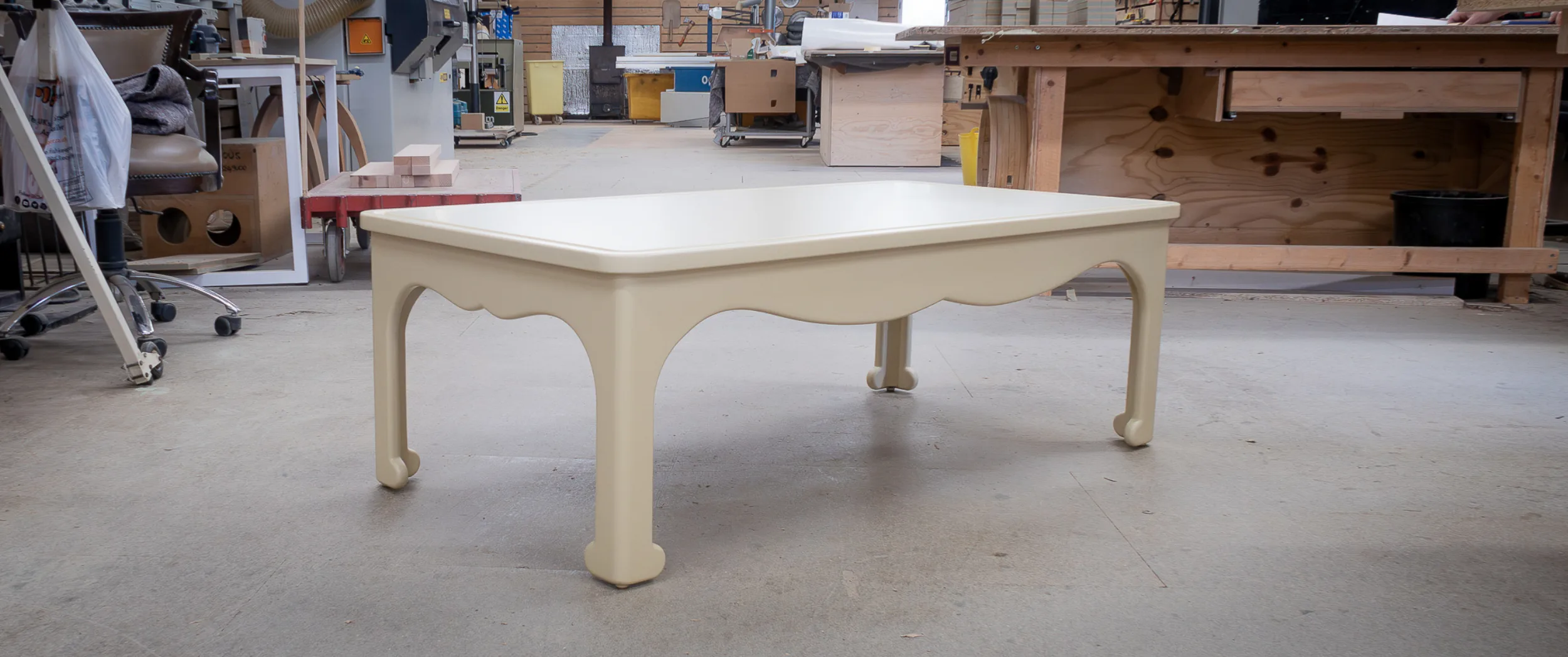 The bespoke low table finished in a pale oil-based ground, its scalloped apron and bracket feet crisply defined, ready for hand-painting.
