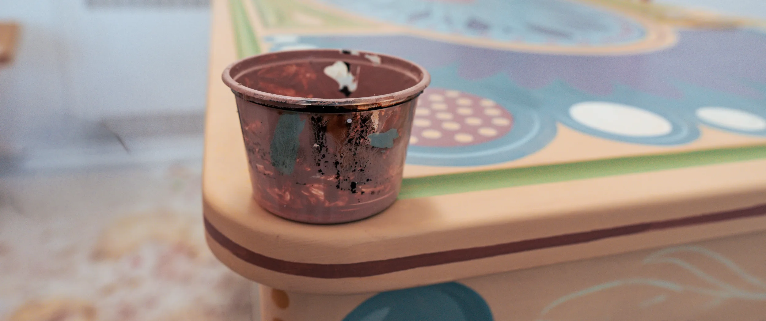 A worn paint pot standing on a part-painted tabletop.