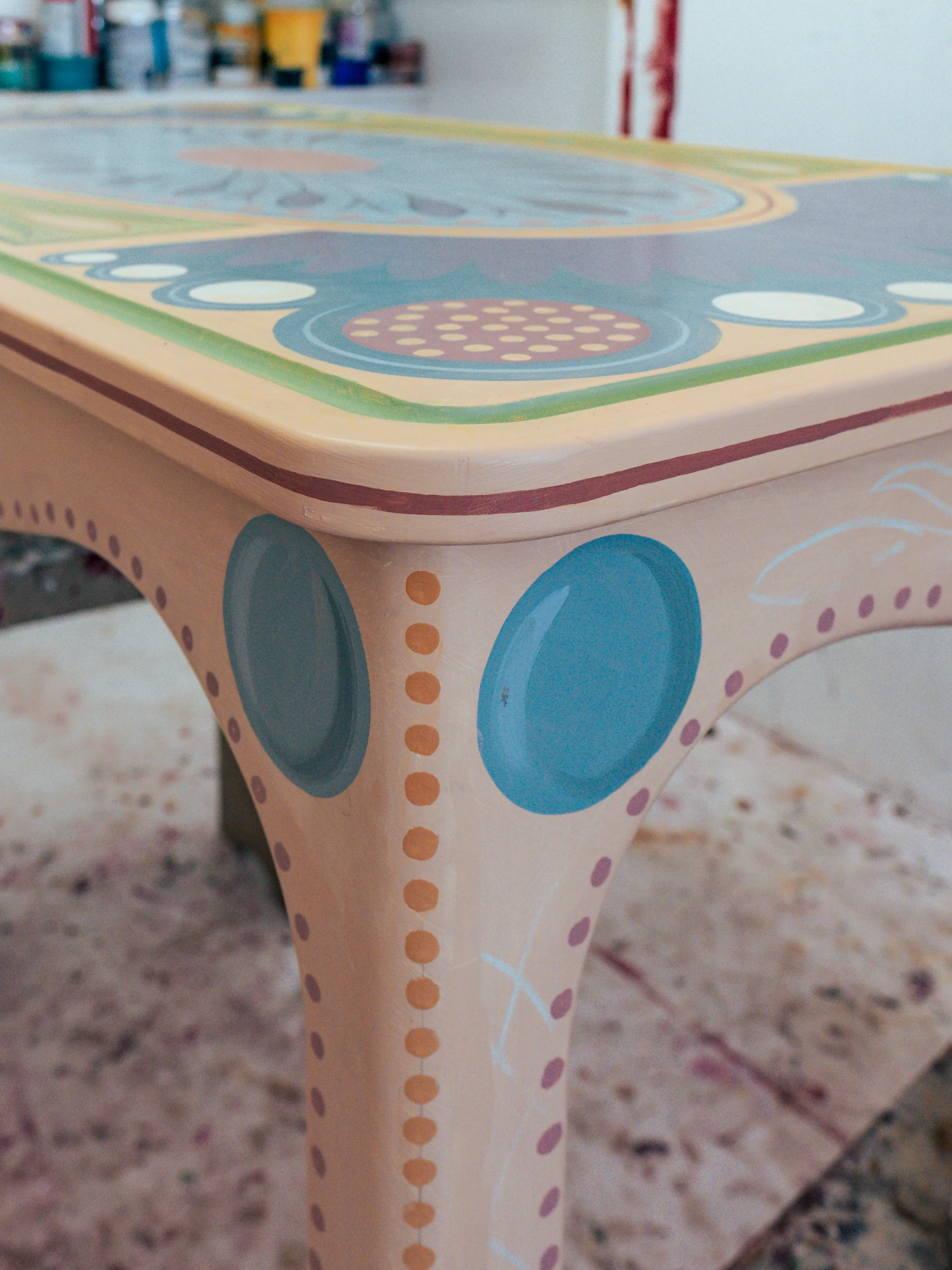 A finished painted leg and apron, with blue roundels and a coral border.