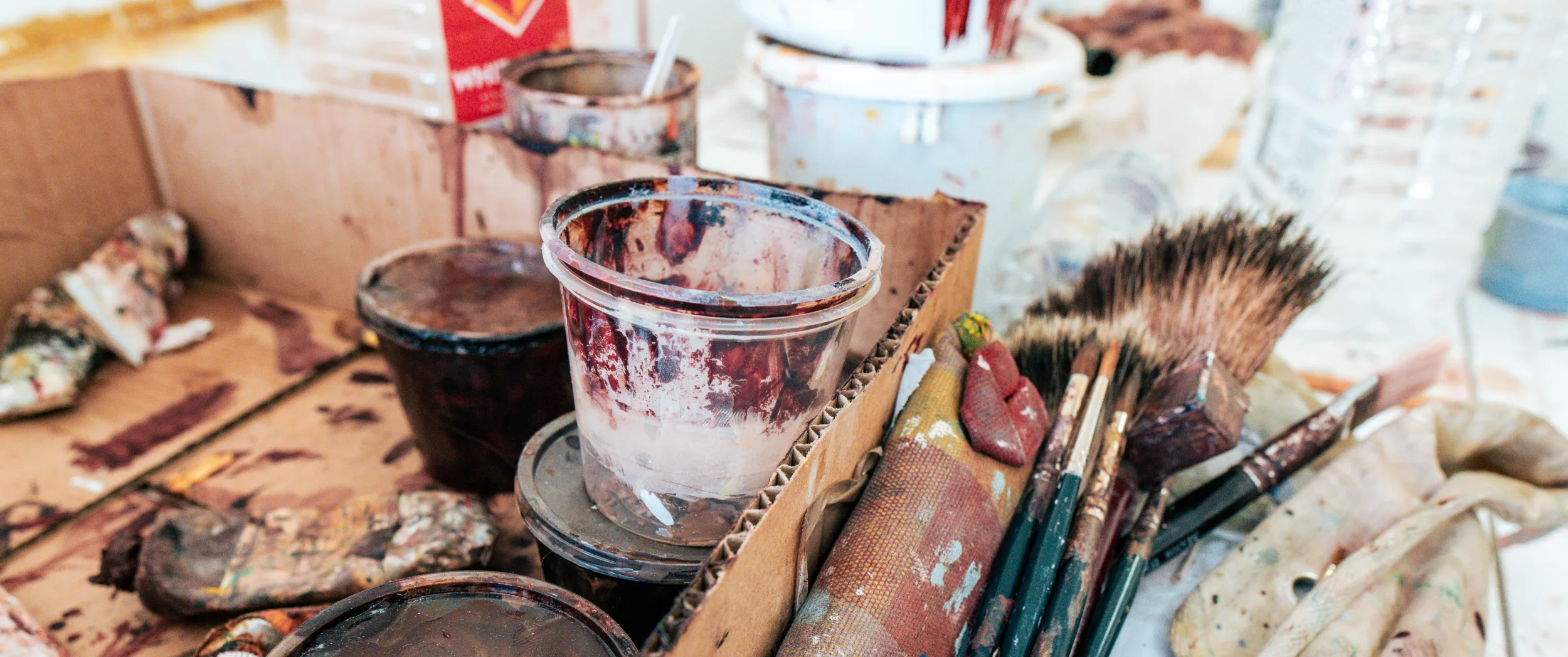 Brushes, pots and a palette on the paint-spattered bench.