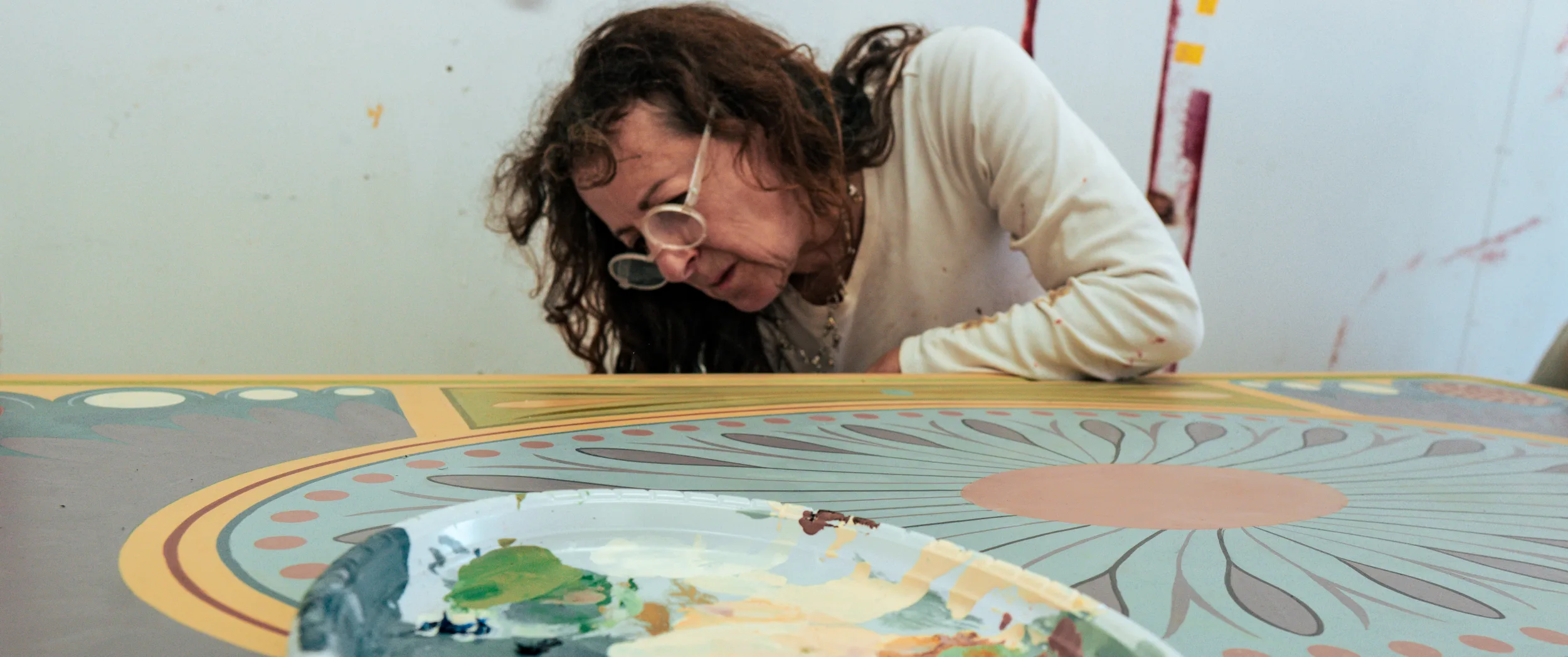 Close portrait of Lizzi Porter, glasses on, mid-brushstroke.