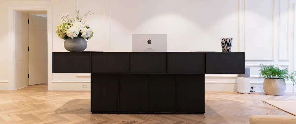 Finished reception desk at 5 St James's Square, with a dark oak front and blackened steel top stretching across the lobby