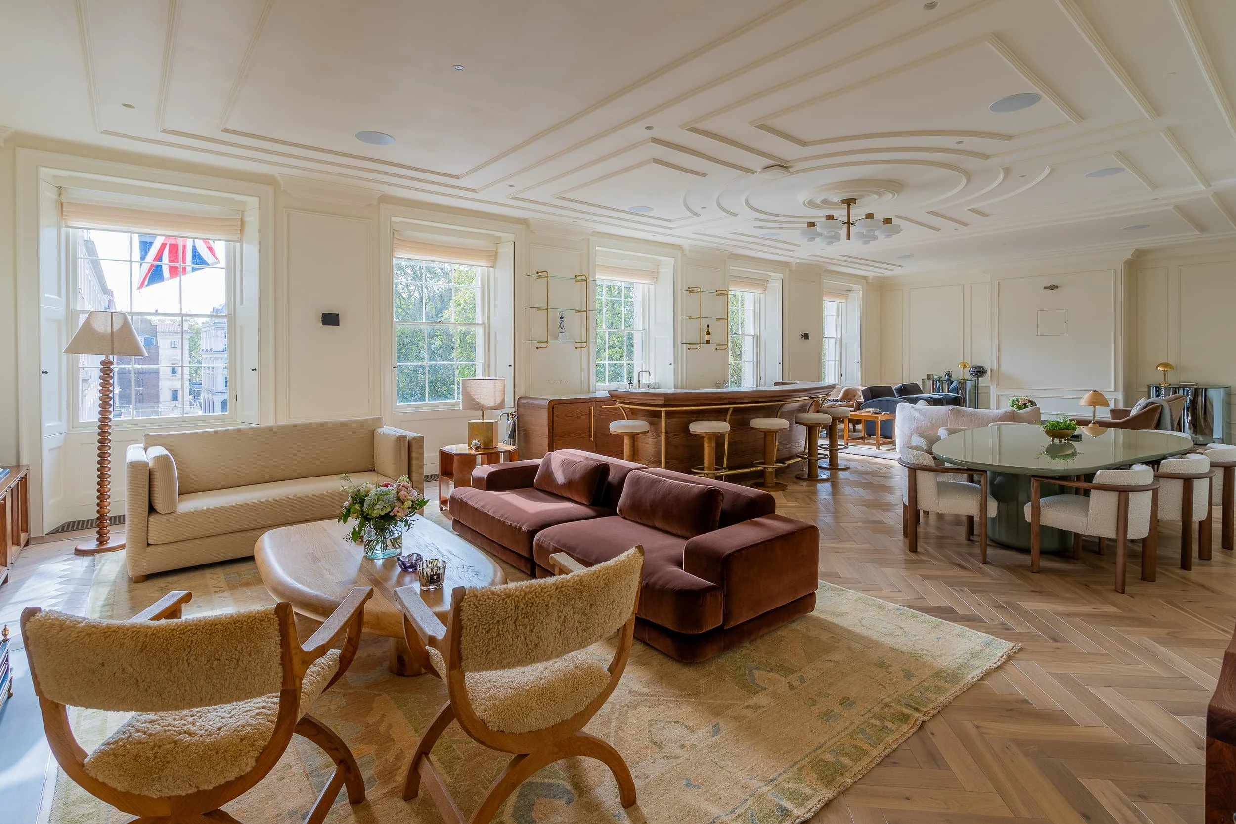 Wide view of the main lounge at 5 St James's Square, with layered seating, bar, dining area and large windows, where bespoke sofas and casegoods create a club-like, apartment-style office interior.