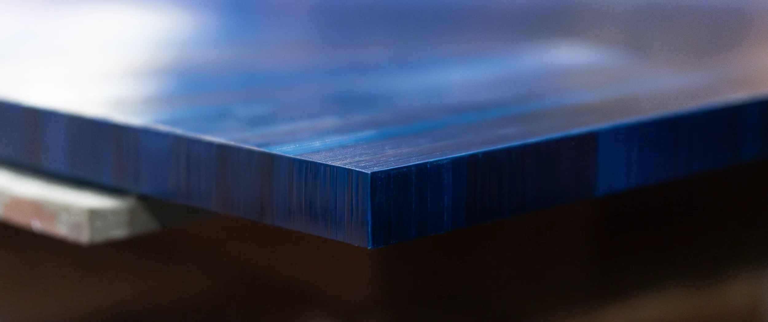 Macro of a finished blue straw-marquetry panel corner, the dyed fibres running crisp to the edge.