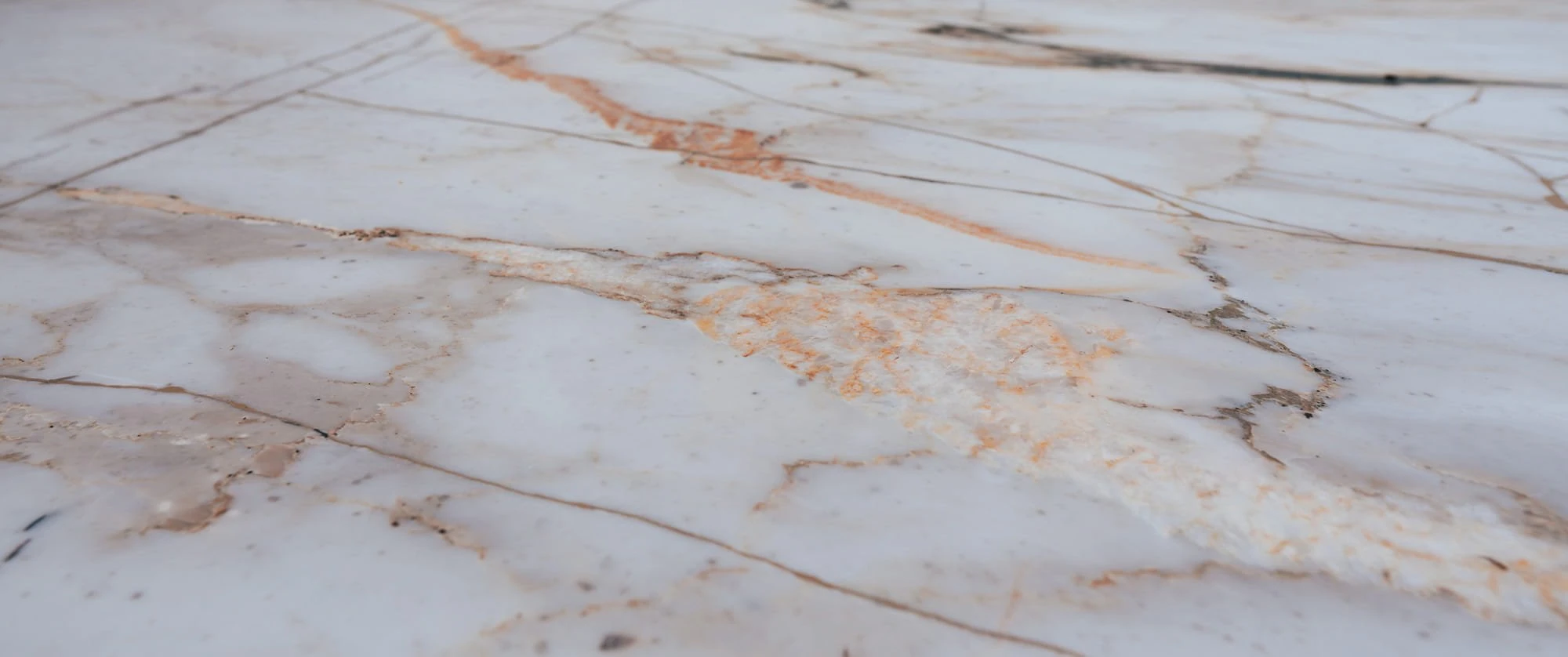 Close view of the pale marble worktop at the Glass House, with rust and grey veining running across the honed surface.