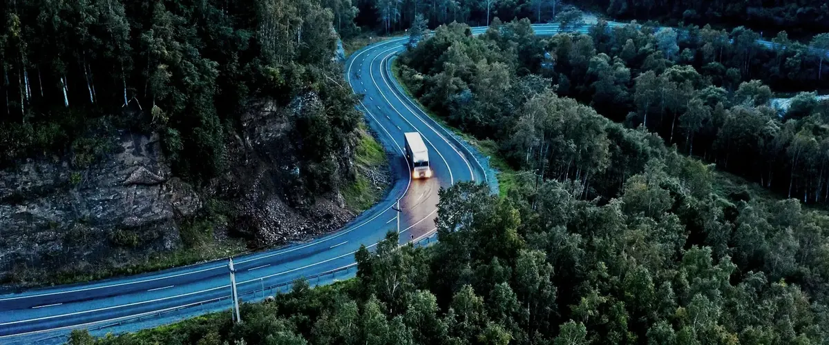 Delivery lorry on a winding wooded road, white-glove delivery of bespoke furniture