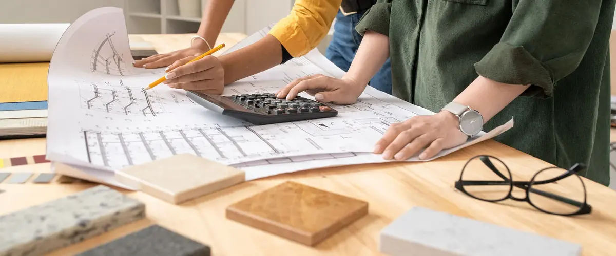 Colleagues reviewing drawings with a calculator and stone and timber samples, design development